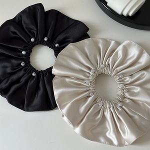 Detailed view of high-quality satin scrunchies in black and beige with pearl accents