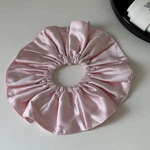 Detail of pink satin scrunchie with white pearls showing smooth texture and luster
