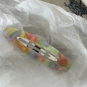 Detailed macro view of an oval acetate hair clip with colorful marbled macaron resin finish
