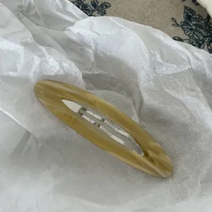Detailed view of handmade acetate hair clip with elegant silver wave pattern and engraving