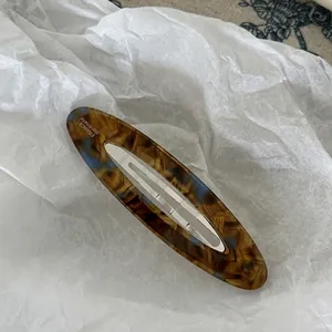 Close-up of tortoise shell acetate oval hair clip with silver metal back and handmade text