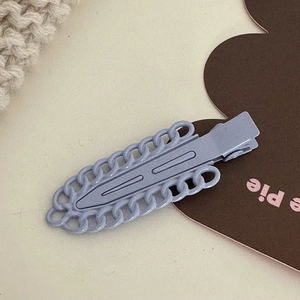 Gros plan sur la barrette en métal lilas avec texture chaîne et design élégant épuré
