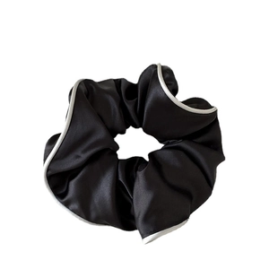 Elegant black satin scrunchie with white contrast piping for a stylish low ponytail