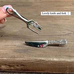Creative liquid metal knife and fork hair clips with pink rhinestones on wood background