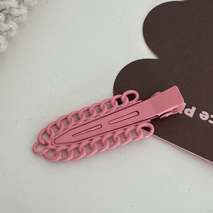 Vue détaillée d'une pince à cheveux en métal rose mat avec motif de chaîne ajouré