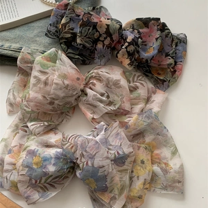 Close-up of three layered chiffon floral bow hair clips with delicate pleated texture