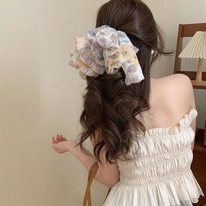 Close-up of floral chiffon oversized scrunchie on model hair in a warm interior
