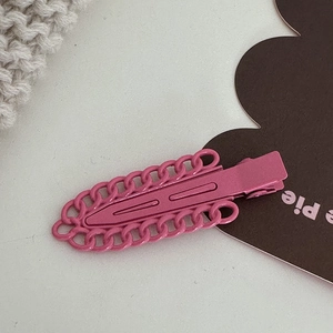 Gros plan d'une pince à cheveux rose mat avec bordure chaîne et attache crocodile