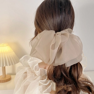 Close-up of beige chiffon layered bow hair clip worn on back of head for a soft elegant look