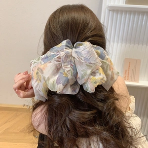 Floral chiffon multi-layer bow hair clip accessory worn on dark wavy hair for women