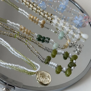 Vue macro détaillée de colliers de perles colorés avec pendentifs fleurs et or love