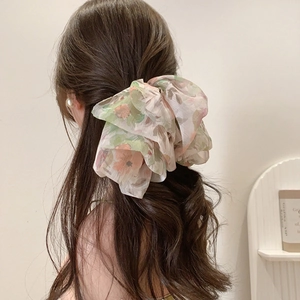 Close-up of a floral chiffon scrunchie with layered fabric design on a ponytail