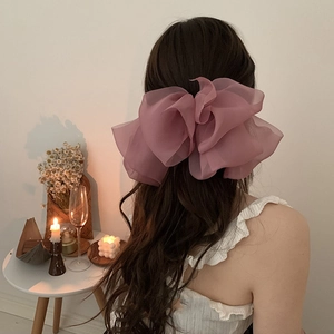 Elegant multi-layered dusty rose chiffon bow hair clip on a model with long wavy hair