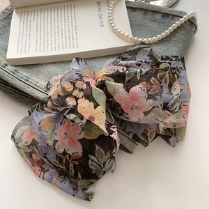 Macro view of floral multilayer oversized bow hair clip on denim with pearls