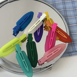 Close-up of colorful matte hair clips with metal base on a mirror surface