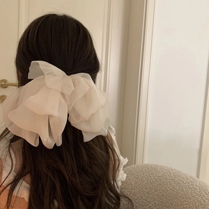 Macro shot of large white multi-layer organza bow hair clip worn on long wavy hair