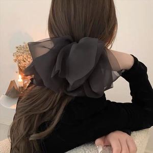 Detail of layered dark grey organza bow hair clip worn on a elegant low ponytail