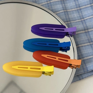 Set of 4 colorful matte seamless duckbill hair clips on a reflective mirror background