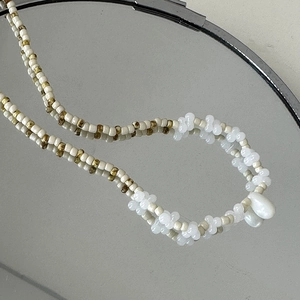 Détail du collier de perles crème avec un pendentif en forme de goutte blanche élégant