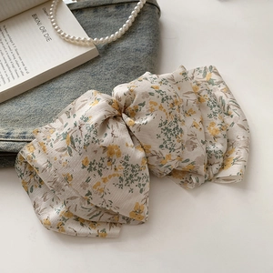 Detail of floral chiffon bow hair clip with yellow flower pattern and spring fastener
