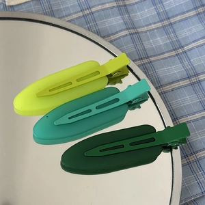 Three-piece matte green seamless hair clips set featuring gradient tones on a mirror