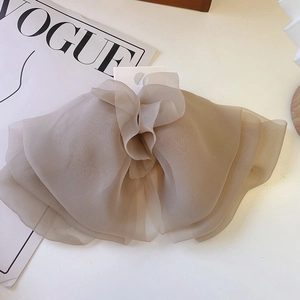 Detailed close-up of layered organza bow hair clip in taupe with translucent fabric texture