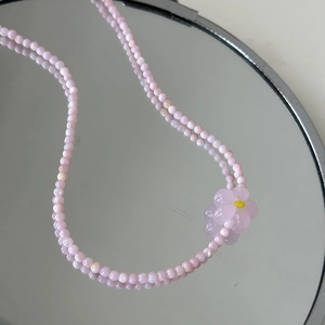 Détail du collier de perles en cristal rose avec pendentif fleur sur miroir