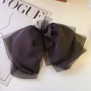 Detail of a large multi-layer black organza bow hair clip on a fashion magazine