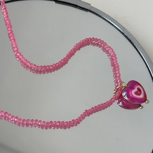 Vue détaillée du collier de perles roses style Y2K avec pendentif cœur sur miroir