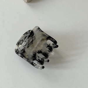 Détail d'une pince à cheveux en acétate à motif marbre avec gravure du logo MY BEAR