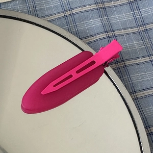 Close-up of pink matte hair clip on a mirror with blue and white checkered background
