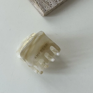 Détail de la pince à cheveux carrée en acétate avec motif écaille ambre et étiquette dorée