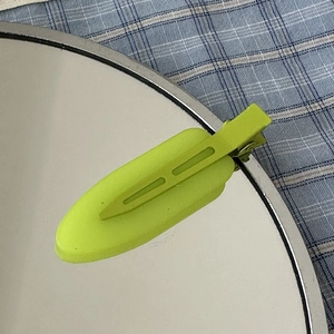 Detailed macro view of a lime green matte hair clip on a round mirror with checkered fabric