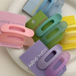 Barrettes ovales aux couleurs pastel assorties posées sur une assiette en céramique blanche