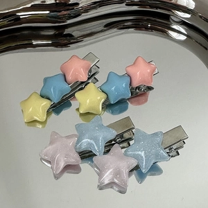 Détail de barrettes étoiles en couleurs macaron et paillettes sur un plateau métallique