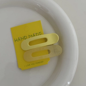Détails des barrettes ovales jaune crème en fini mat et brillant sur leur support