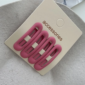 Set of four matte rose pink oval hollow hair clips displayed on a minimalist accessory card