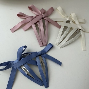 Dettaglio di fermagli a fiocco rosa, beige e blu con tessuto strutturato e base in metallo