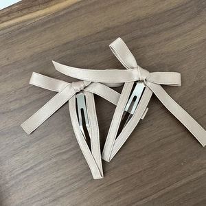 Dettaglio di eleganti fermagli per capelli a fiocco color champagne con clip BB in metallo
