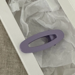 Dettaglio di un fermaglio per capelli ovale viola con finitura opaca verniciata liscia