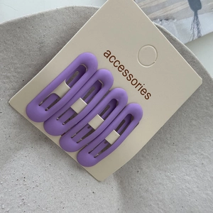 Detail of four matte purple oval hair clips on a card display with accessories text