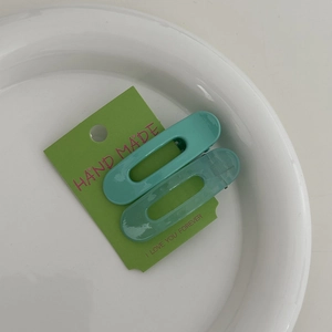 Détail des pinces à cheveux vert menthe sur une carte artisanale posée sur une assiette