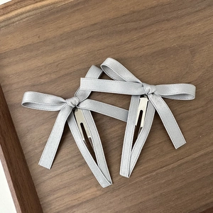 Dettaglio di fermagli per capelli con fiocco in raso grigio e base in metallo silver