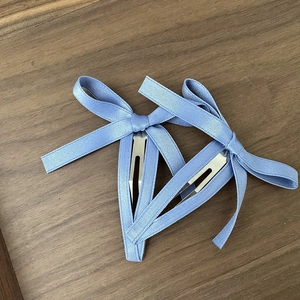 Dettaglio di fermagli per capelli a fiocco azzurro con nastro strutturato e clip metalliche