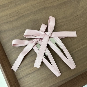 Dettaglio di fermagli per capelli con fiocco in seta rosa su legno scuro
