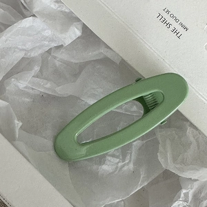 Dettaglio di un fermaglio per capelli ovale verde opaco con clip a becco d'anatra