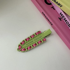 Detalle de la pinza para el pelo tejida en rosa y verde para un peinado de moda actual