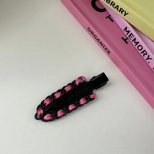 Detalle de una pinza para el cabello de cadena de metal negro con cinta de raso rosa suave