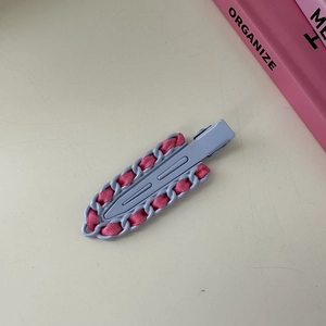 Detalle de pinza para el pelo en metal violeta con cinta rosa tejida tipo cadena