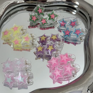 Gros plan de barrettes à cheveux étoiles pailletées sur un plateau en miroir argenté